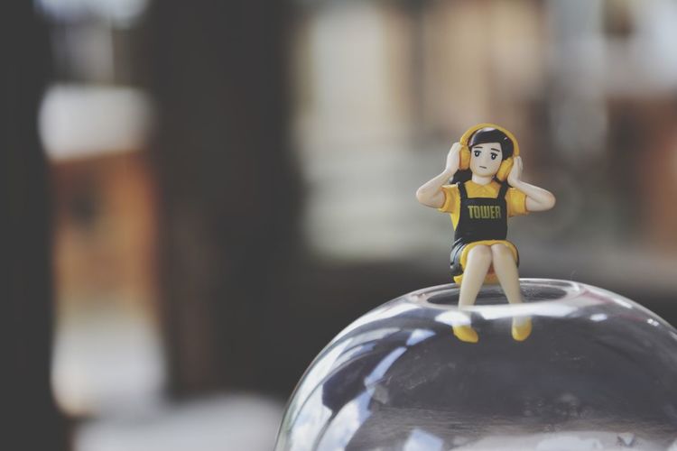 Close-up of female figurine using headphones on crystal ball at home