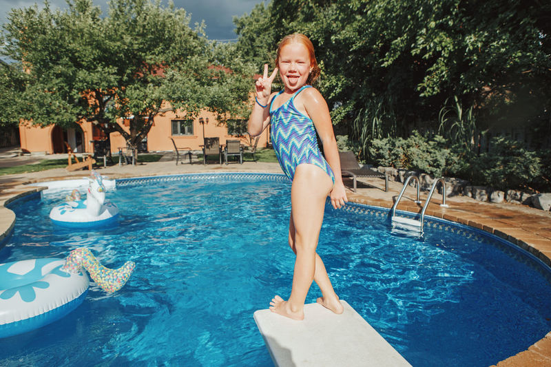Portrait of girl standing by swimming pool