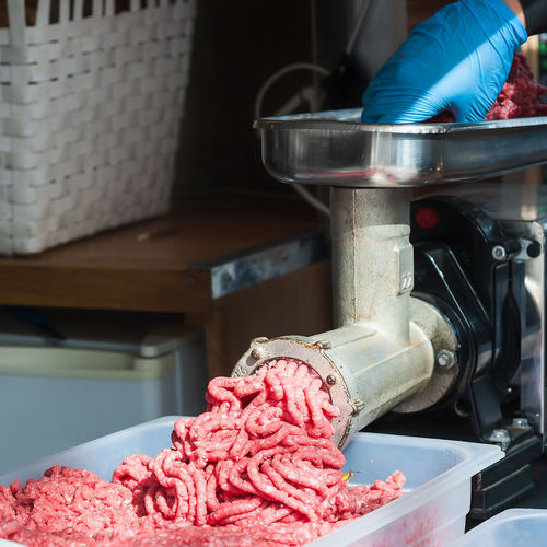 Cropped image of person grinding meat