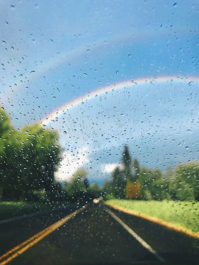 Road seen through wet glass window in rainy season