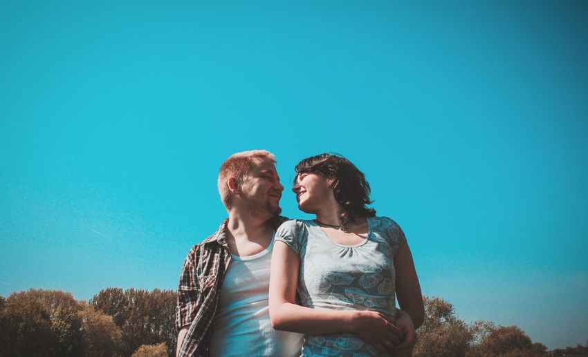 Young couple smiling against clear blue sky