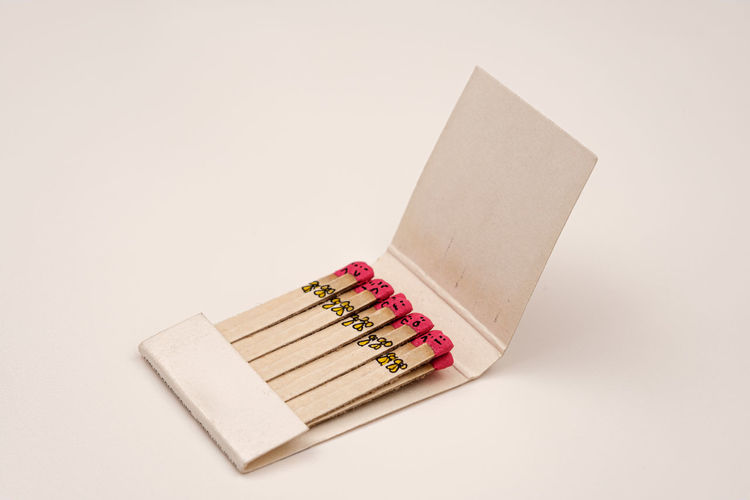 Matchsticks with faces painted on the heads on white on white