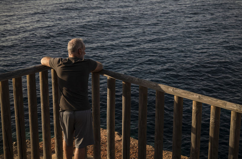 Rear view of adult man looking at sea in summer