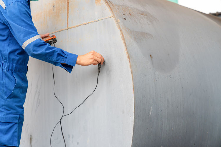 Engineering inspect the thickness wall of tanks with a device while working at height.