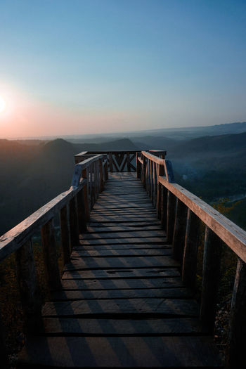 Empty long wooden footbridge against clear sky