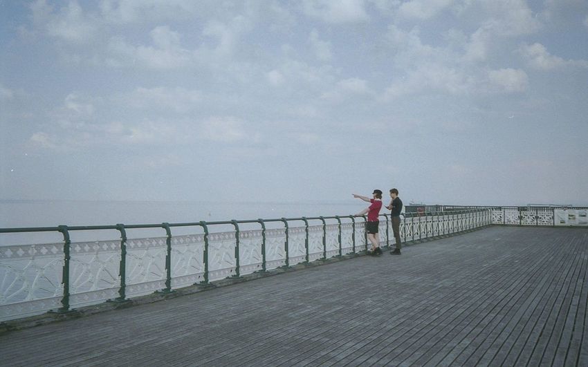People standing on pier over sea against sky