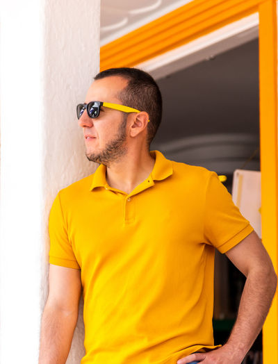 Midsection of man wearing sunglasses standing against wall