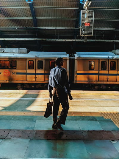 Full length rear view of man walking at railroad station platform