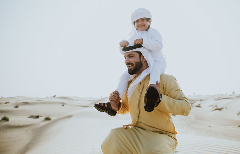 Father carrying son on shoulder in desert