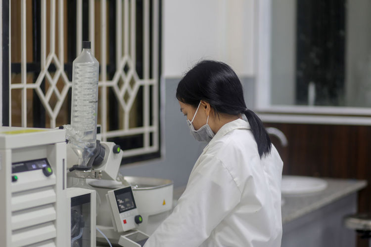 Asian woman scientist operating a rotary evaporator to make an experiment in the laboratory
