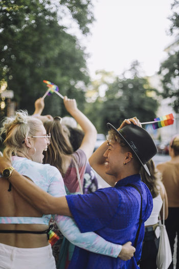 Happy young man wearing hat while enjoying with female friend at gay pride parade