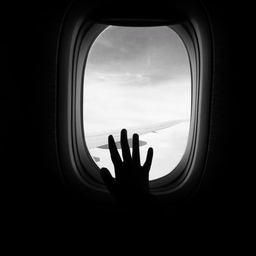 Silhouette hand of person on airplane window