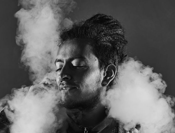 Close-up of man smoking against white background