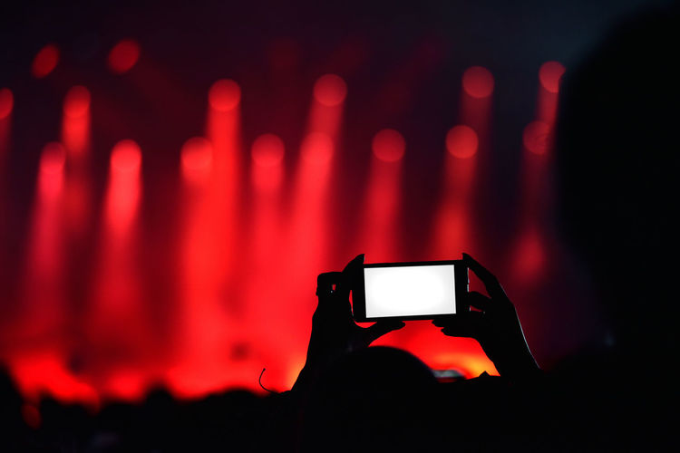 Close-up of hand photographing with smart phone during concert