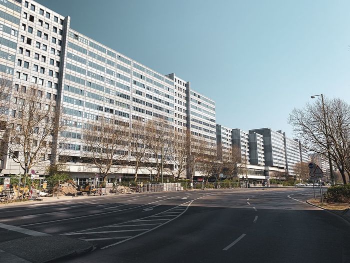 Road by buildings against clear sky