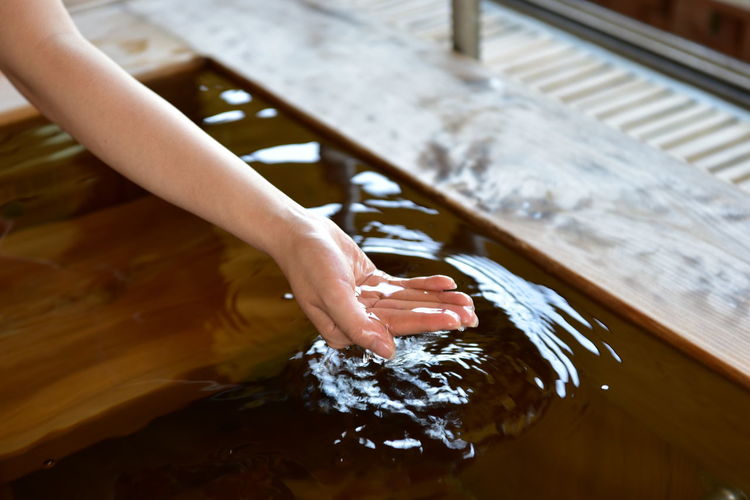 Cropped hand of woman touching water in hot spring