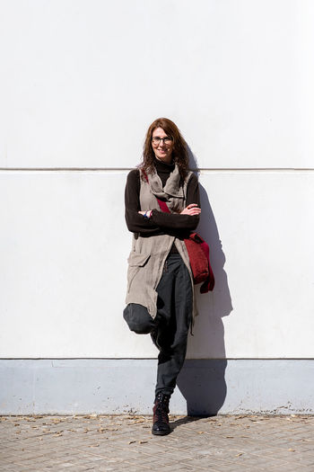 Full length portrait of woman standing against wall