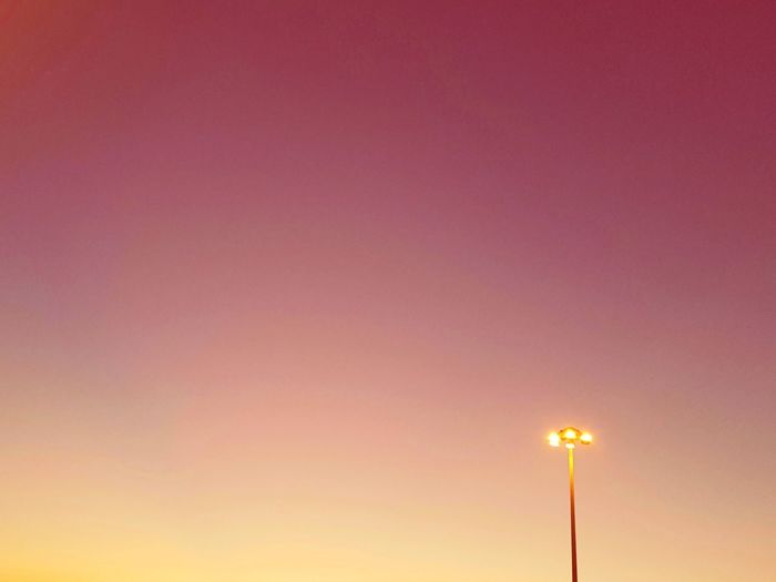 Low angle view of illuminated street light against sky at sunset