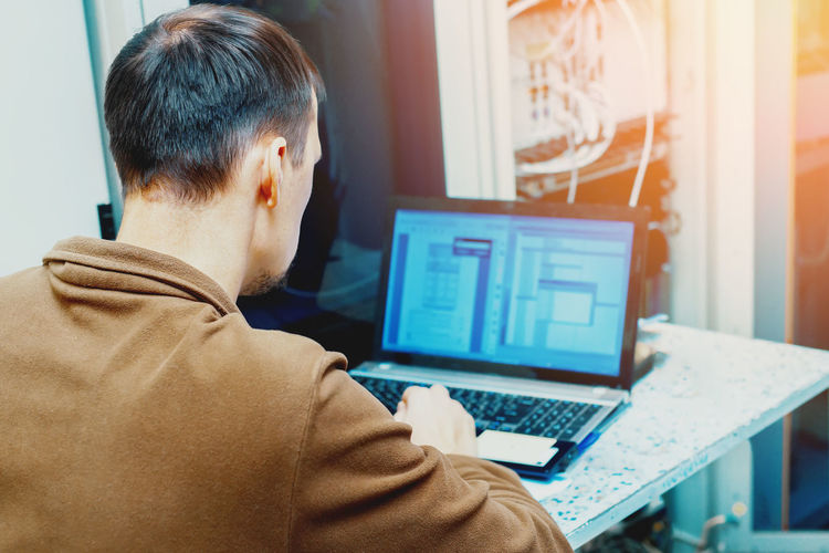 Rear view of man using laptop