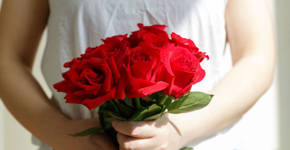 Midsection of woman holding roses at home
