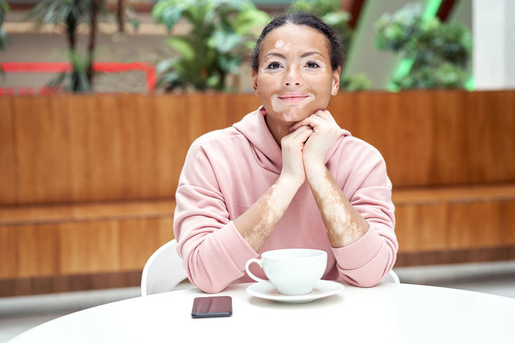 Portrait of woman with coffee cup sitting on table