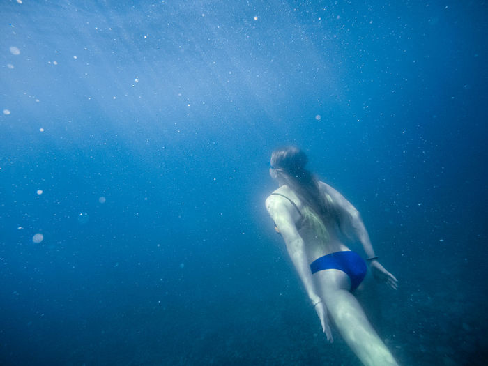 Girl swims underwater in the black sea