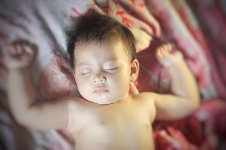 Close-up of cute baby girl on bed