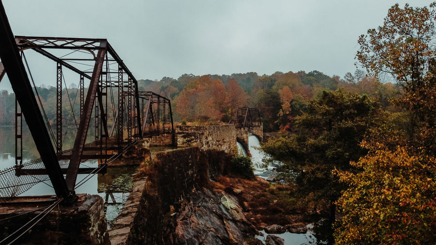 Bridge over forest against sky during autumn
