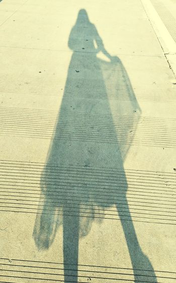 Shadow of person on footpath in city