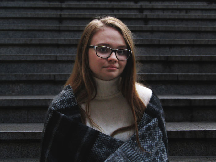 Portrait of young woman wearing eyeglasses against steps