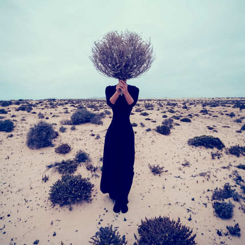 Fashion photo. girl in the desert with a bouquet dead branches