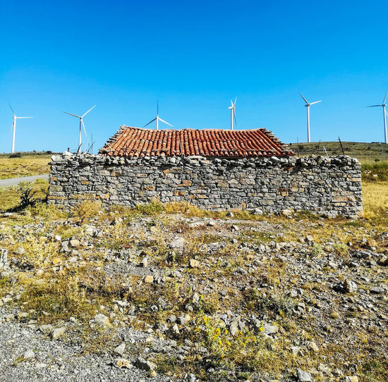 Traditional windmill on field against blue sky