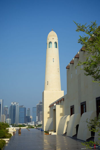 Lighthouse by sea against clear sky