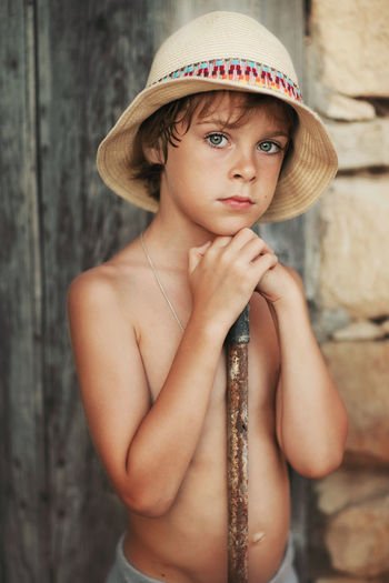 Portrait of shirtless boy against wall