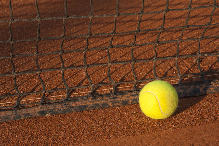 Close-up of yellow tennis ball by net