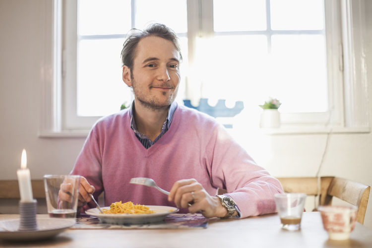 Portrait of man smiling while eating pasta