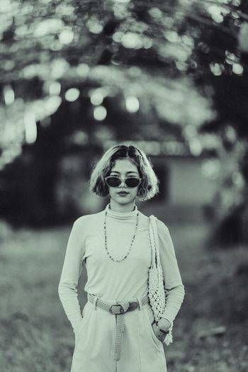 Portrait of young woman wearing sunglasses while standing on land