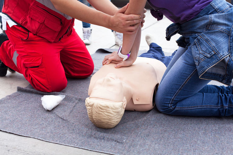 Instructor guiding woman to perform cpr on dummy