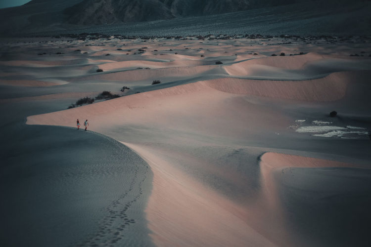 Two people hiking on ridge of sand dune in death valley national park