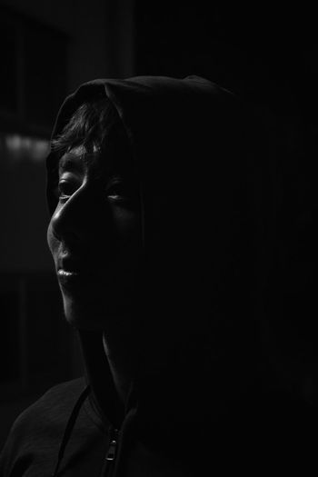 Close-up of young man looking away against black background