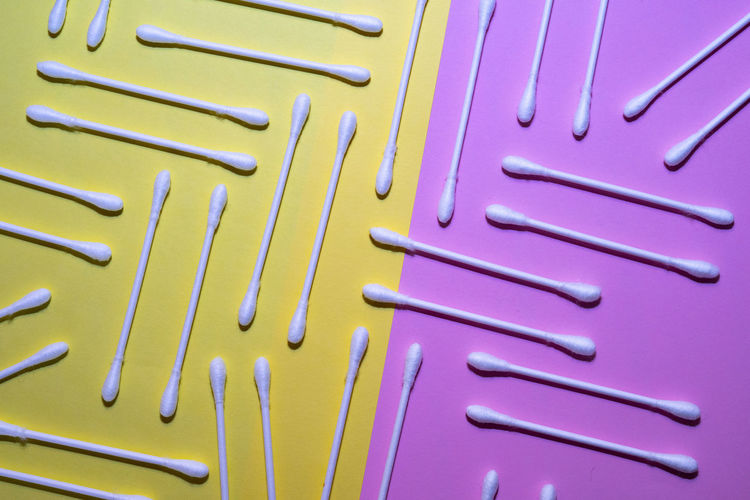 Cotton swabs on a pink and yellow background.