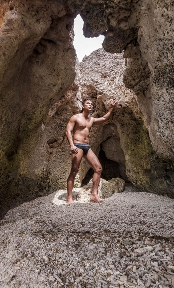 Full length of shirtless man standing in cave