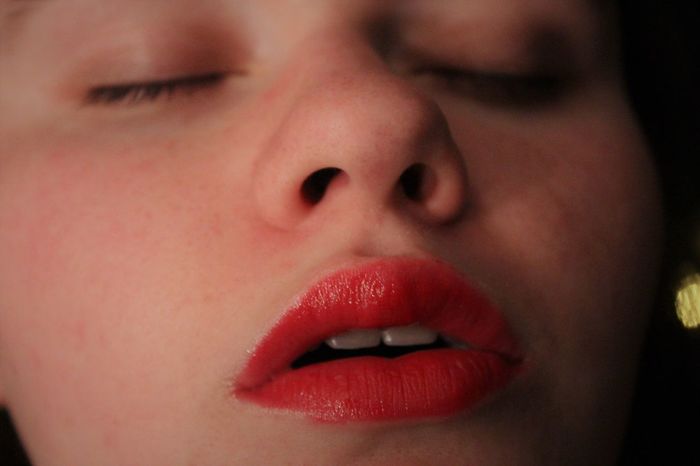 Close-up of sensuous woman with eyes closed and red lipstick