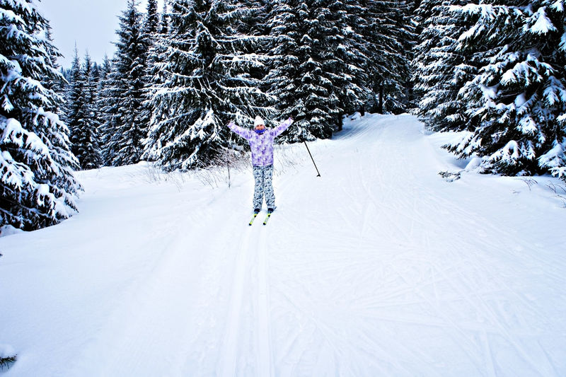 Young happy woman in winter ski clothing skiing in a beautiful coniferous fir forest. winter sport