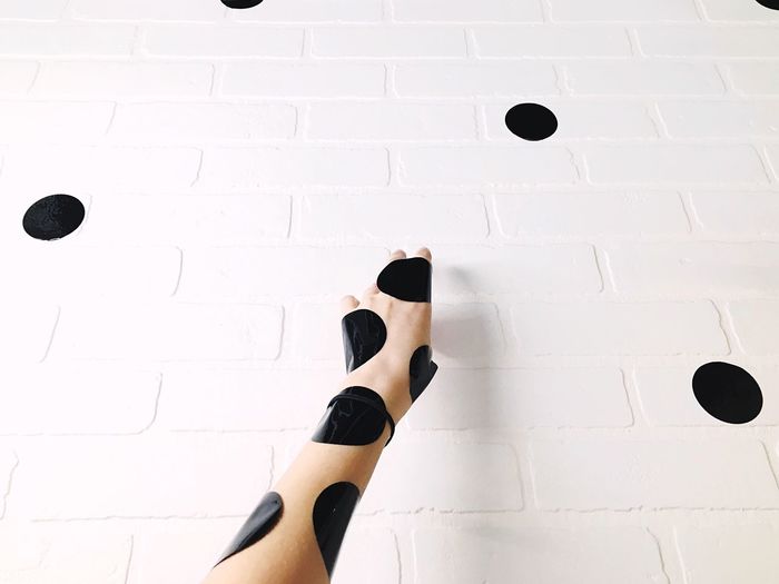 Cropped image of hand with dots on white wall