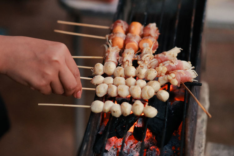 Midsection of person preparing food on barbecue grill
