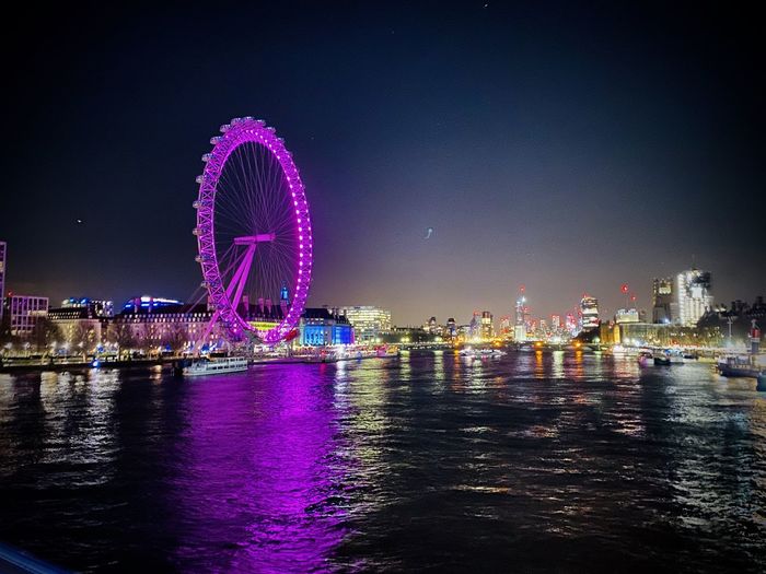 Illuminated ferris wheel in city at night