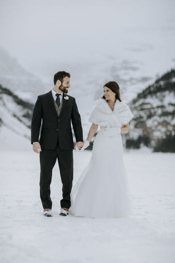 Bride and groom in love on ice on frozen lake in mountains in winter