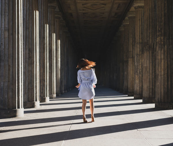 Rear view of woman standing at colonnade