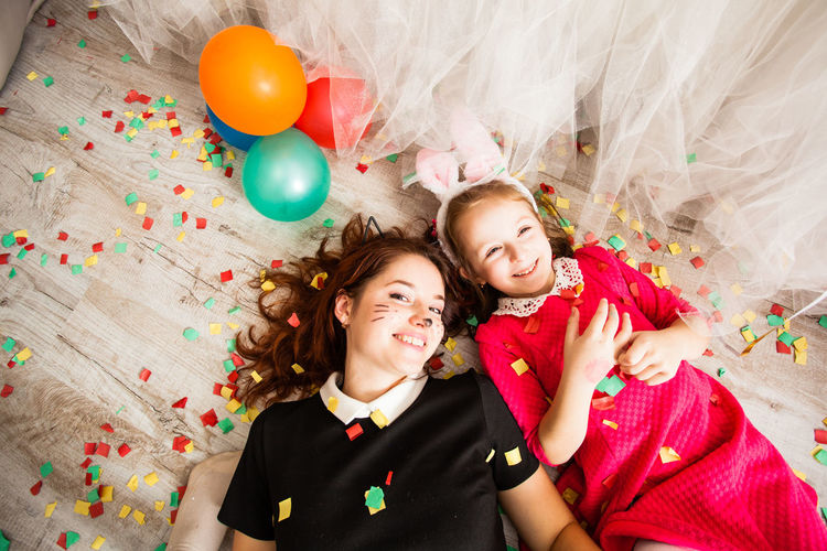 Portrait of mother and daughter lying down on bed at home